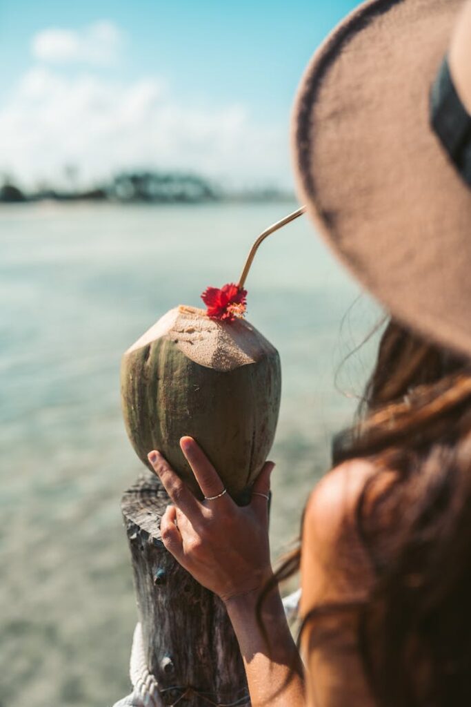 A woman holding a coconut drink on a tropical beach in Zanzibar, Tanzania.
